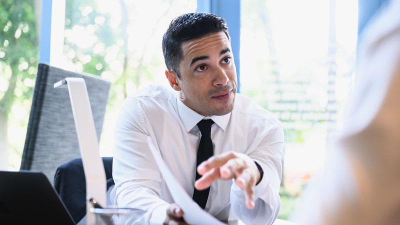 Businessman wearing a white shirt pitching an idea on paper to a client