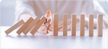 hand stopping dominoes from falling signifying avoidance of risks and legal complexity