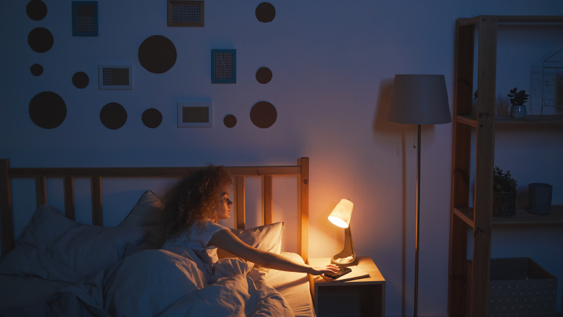 woman turning off lamp before going to sleep