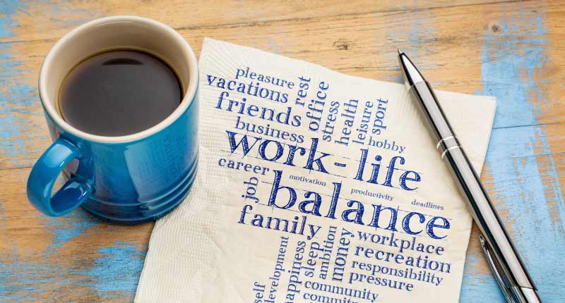 coffee mug, pen, and a page on the table with text highlighting work life balance