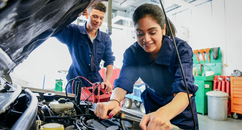 two car mechanic apprentices working in garage and learning mechanical skills