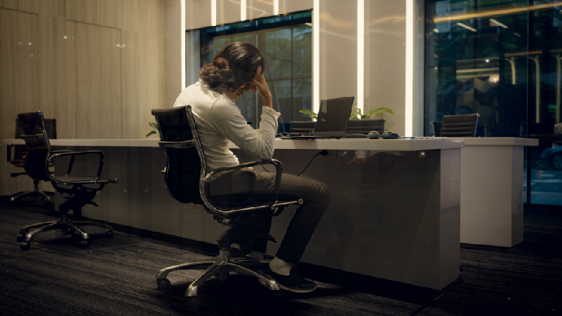 Side view of young businesswoman sitting at desk in office looking away