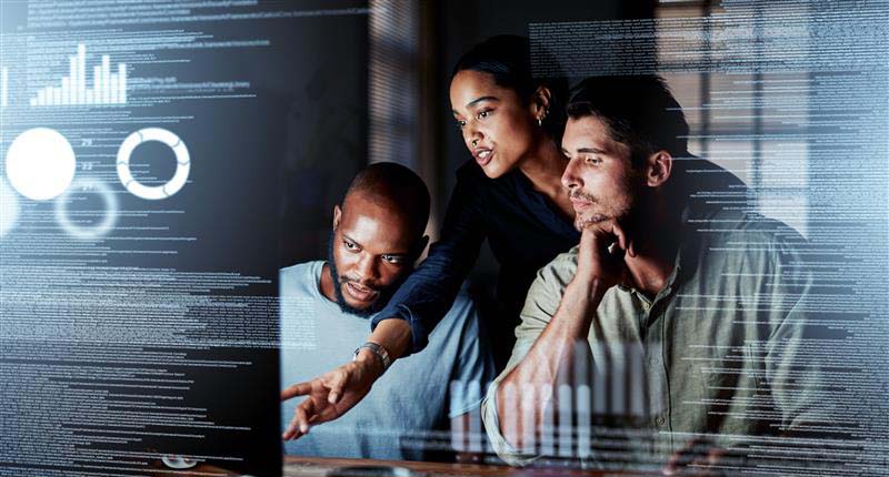 Shot of a group of programmers working together on a computer code at night