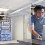Engineer using a laptop behind glass