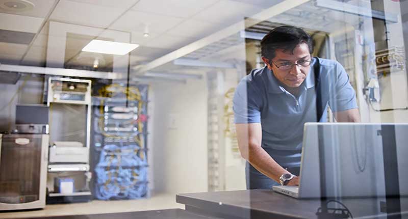 Engineer using a laptop behind glass