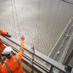 Bridge workers in work overalls meeting on top of a bridge