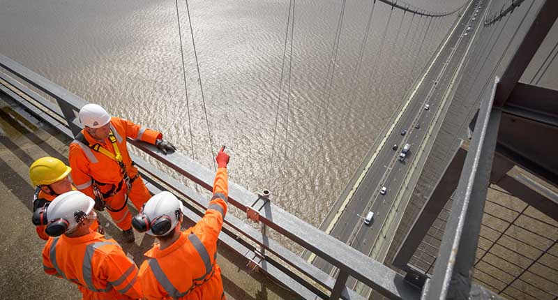 Bridge workers in work overalls meeting on top of a bridge