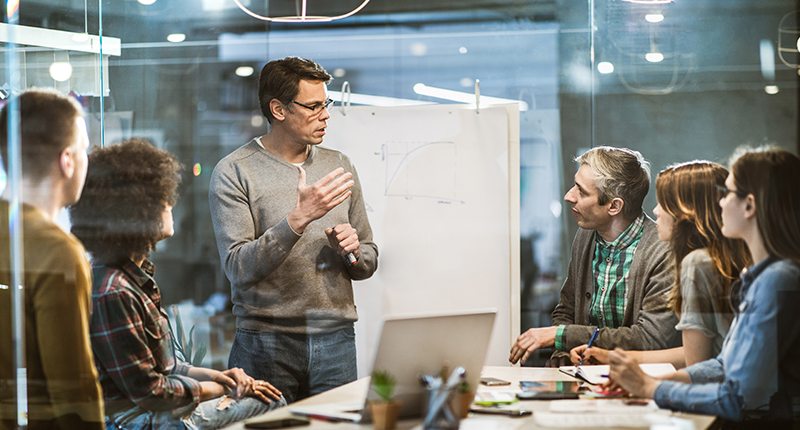 Mid adult manager talking while having presentation with his team in the office
